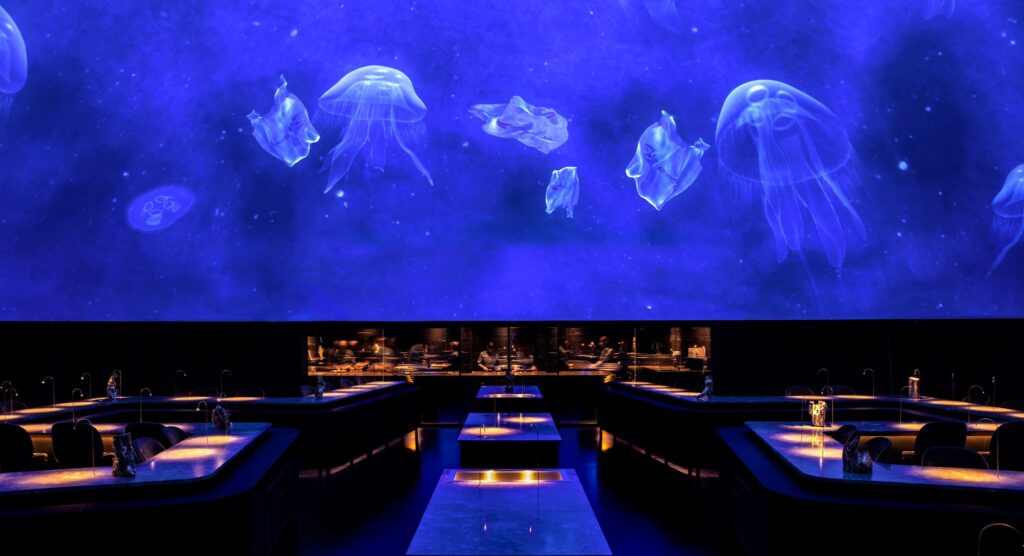 Gastronomy, theatre, art and spectacular visuals blend to create the Alchemist universe. A fine dining experience is the core of the restaurant – but keeping with the idea of Holistic Cuisine the servings are augmented by performers, installations and the architecture itself.
Most of the drama at Alchemist actually happens on the plates, where layers of subtext, both humorous and serious, line the 50 “impressions” that constitutes the Alchemist experience. Rasmus Munk’s gastronomy is Nordic at heart but far reaching in terms of inspiration and flavours.